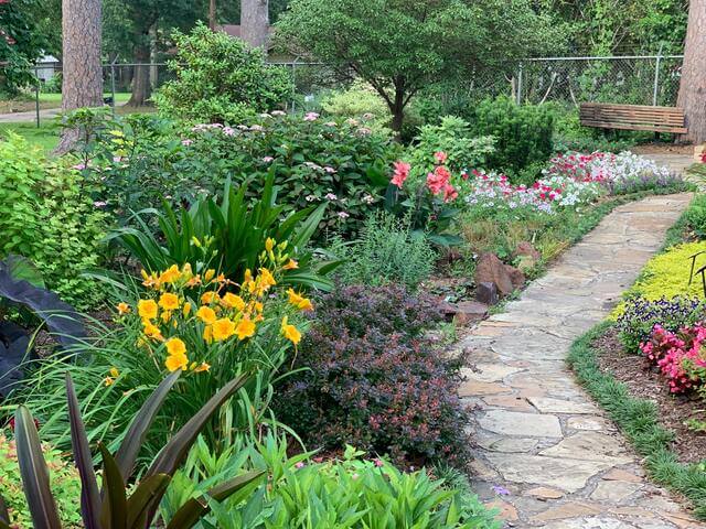 Stone pathway winding through a colorful garden of flowers and bushes