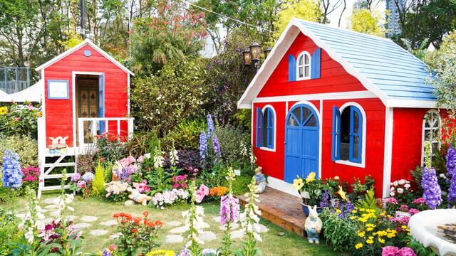 Colorful flowers surrounding two red sheds in a garden