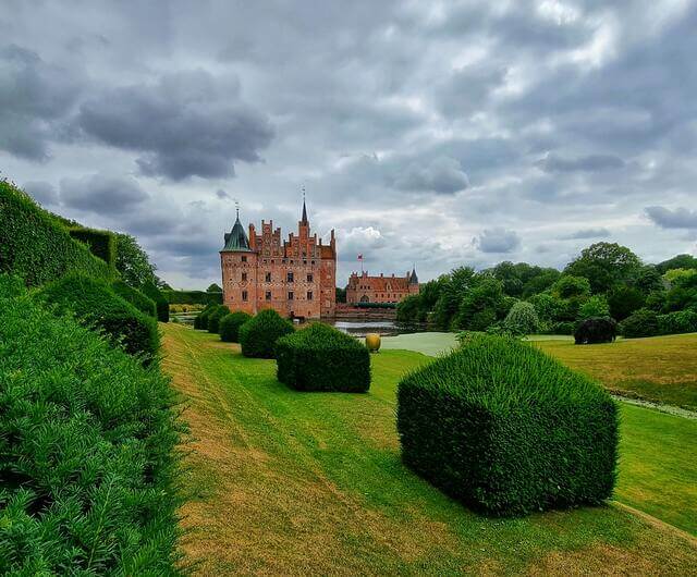 Fresh cut lawn with a row of neatly cut bushes and a castle in the background