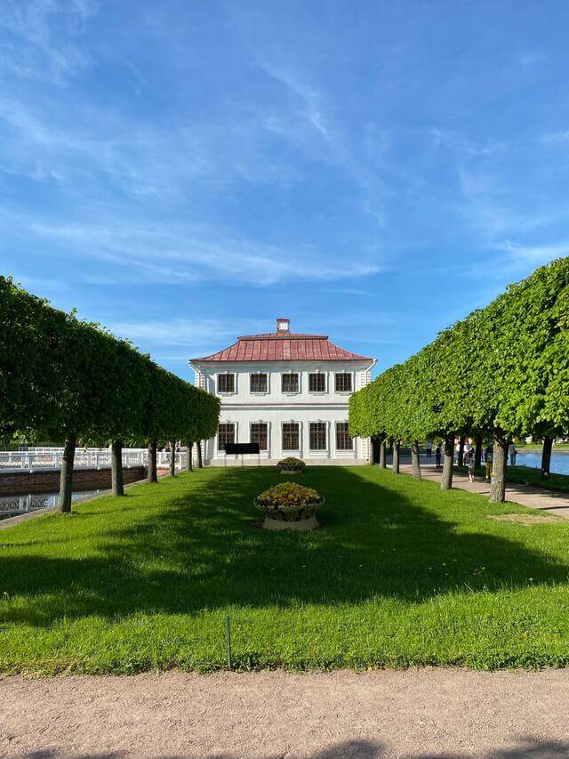 Nicely cut lawn in front of a house lined with neatly cut trees on the sides